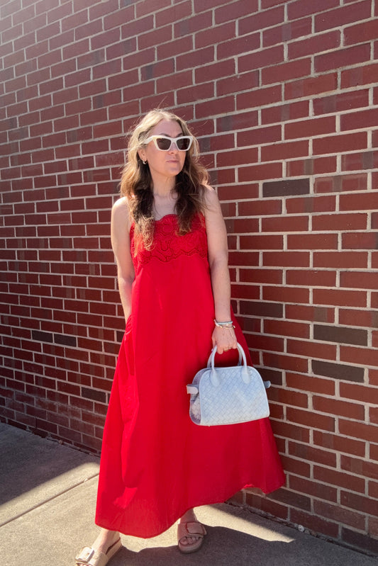 Woman in a red dress standing on a brick pavement
