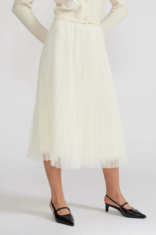 Person wearing a white pleated skirt with a plain background