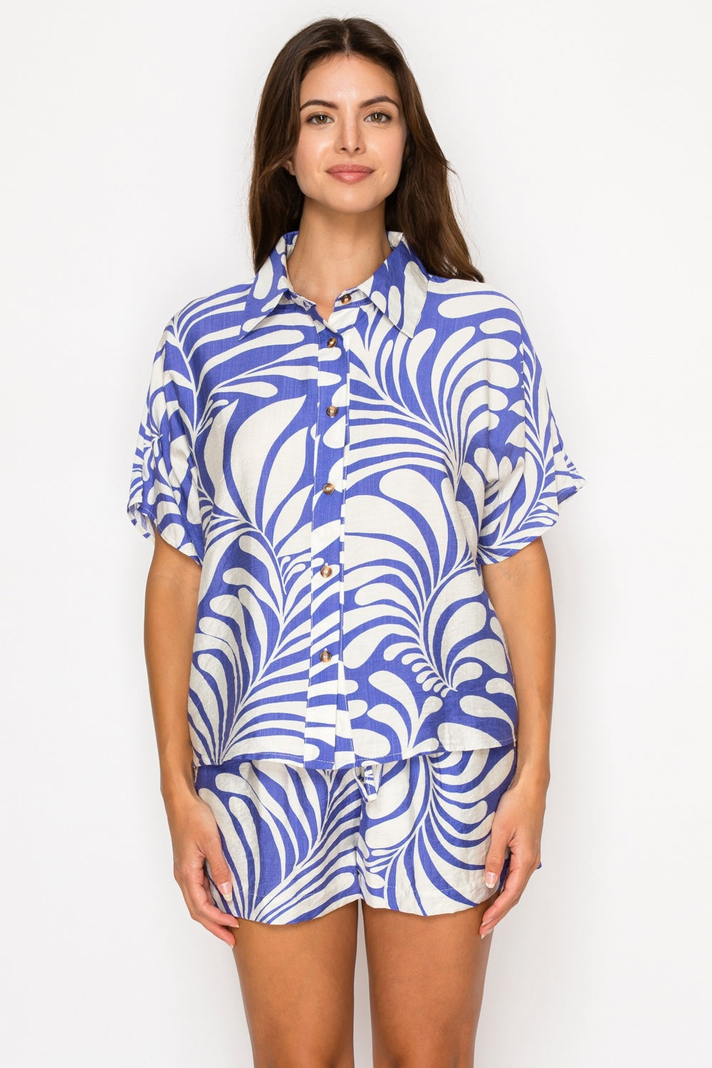 Woman wearing a blue and white patterned shirt and shorts on a white background