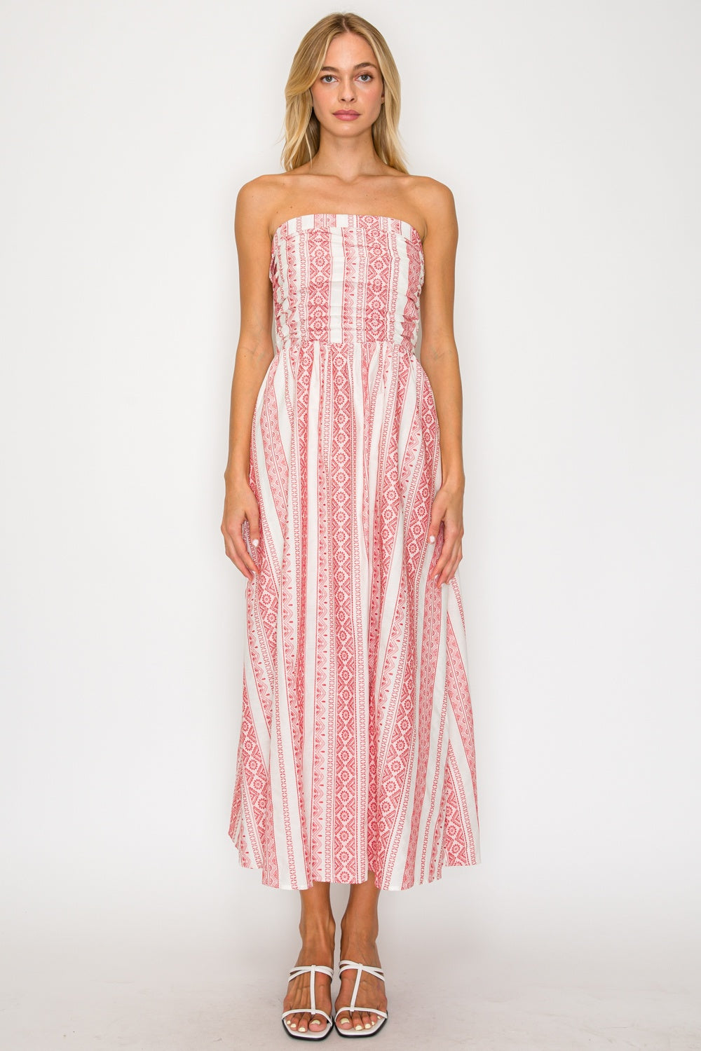 Woman wearing a strapless red and white patterned dress on a white background
