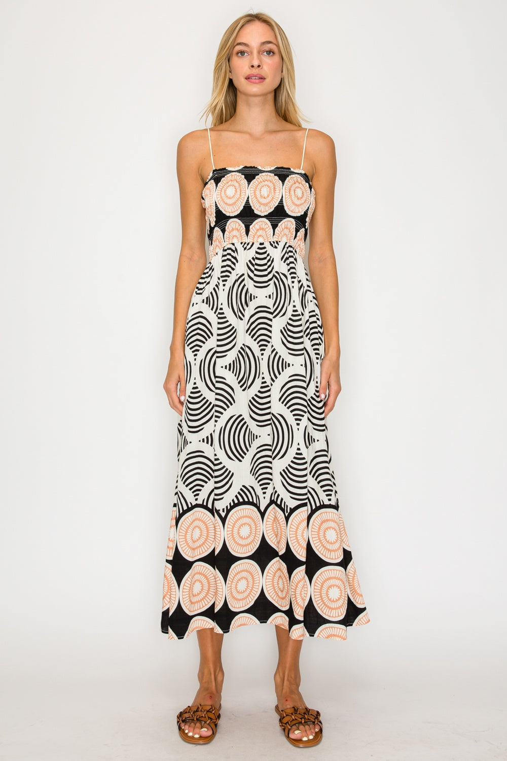 Woman wearing a black and white patterned dress with pink floral accents on a white background