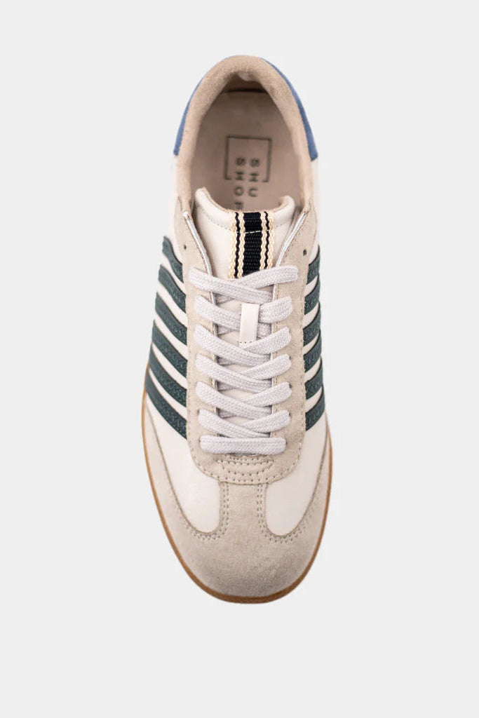 Sneaker with white laces and green stripes on a light gray background