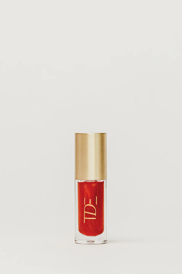 Red lip gloss with gold cap on a light gray background