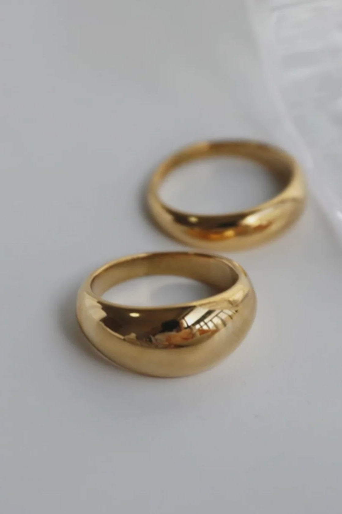 Two gold rings on a light gray background