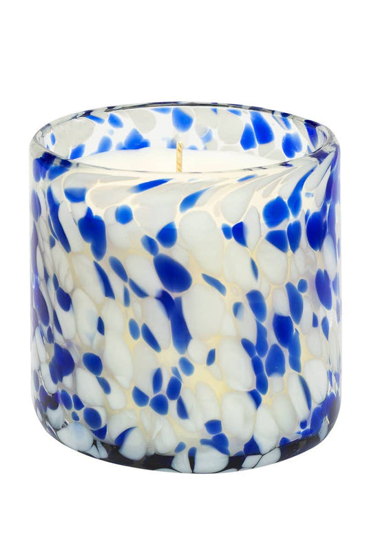 Candle in a blue and white speckled glass container on a white background