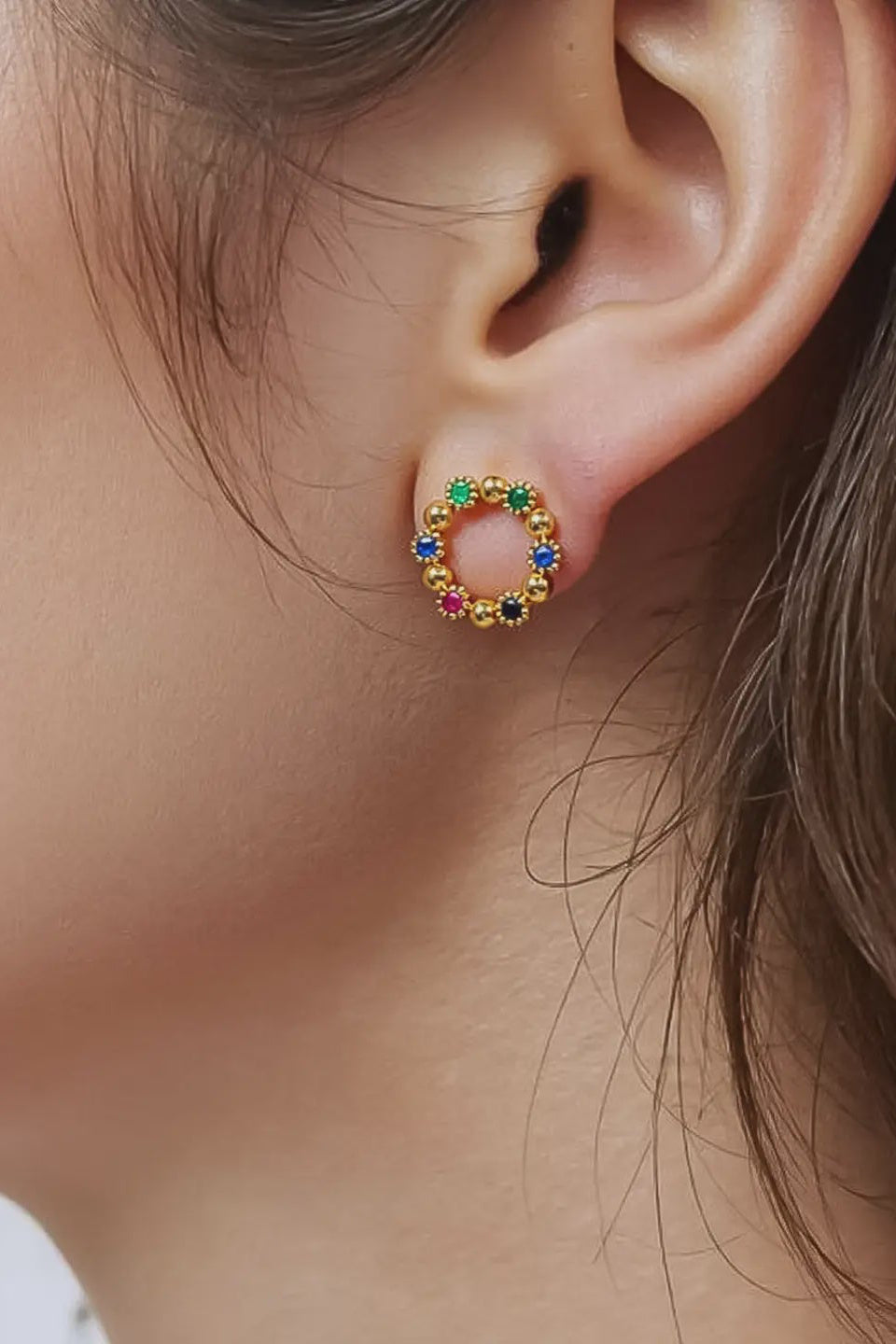 Close-up of an ear wearing a colorful circular earring.
