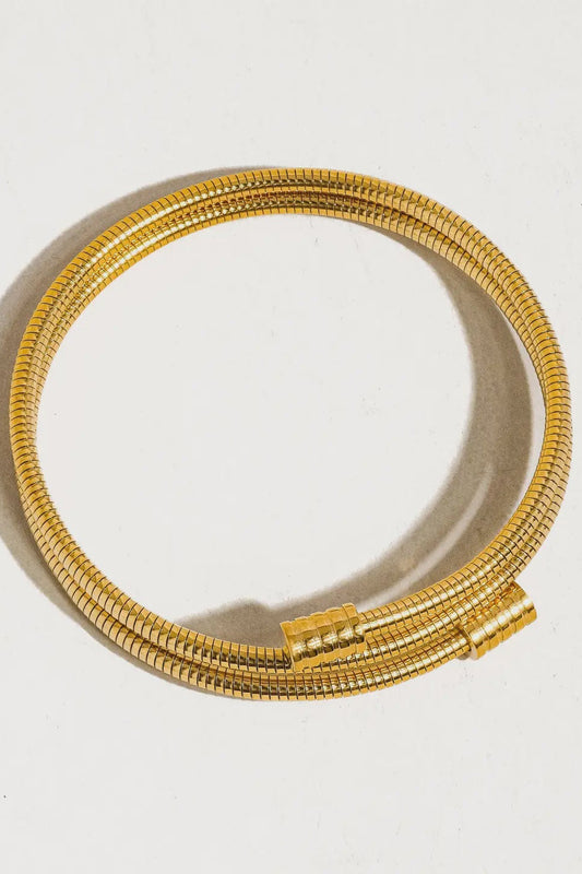 Gold bracelet on a light gray background