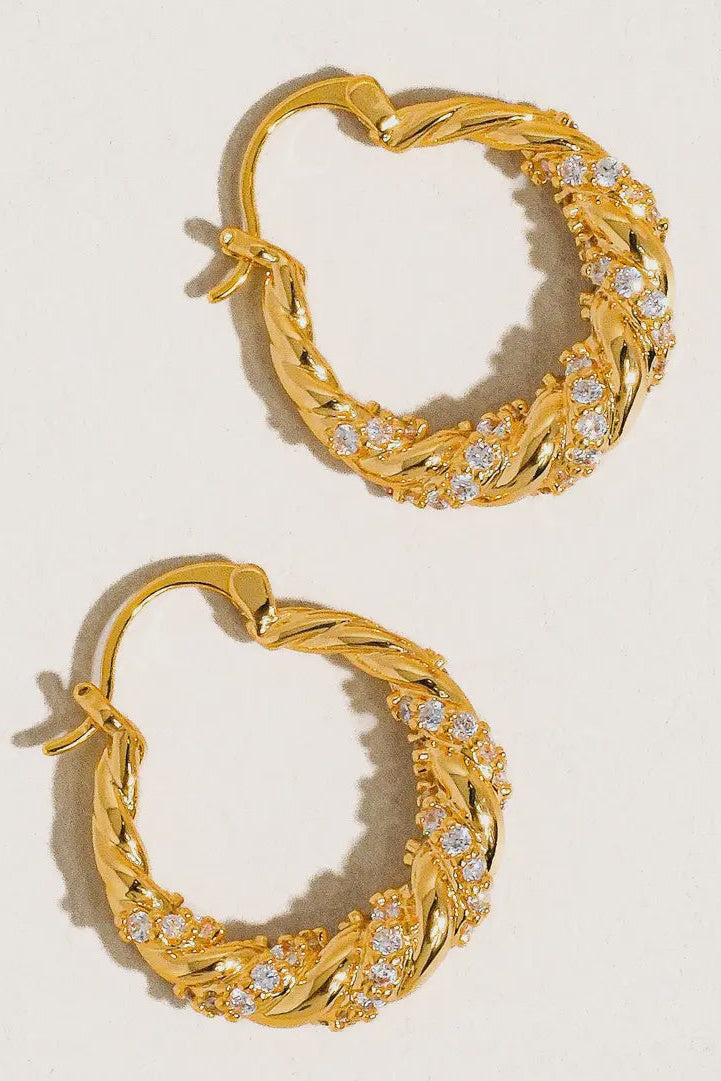 Pair of gold hoop earrings with diamond accents on a light background