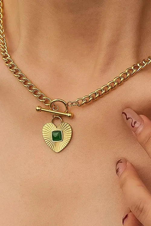 Gold chain necklace with a heart-shaped pendant worn by a person