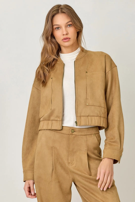 Woman wearing a beige jacket and pants set on a plain background