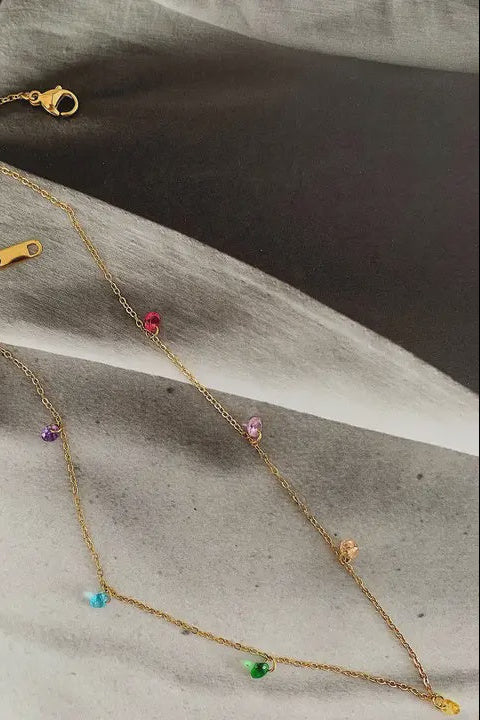 Gold necklace with colorful beads on a textured surface