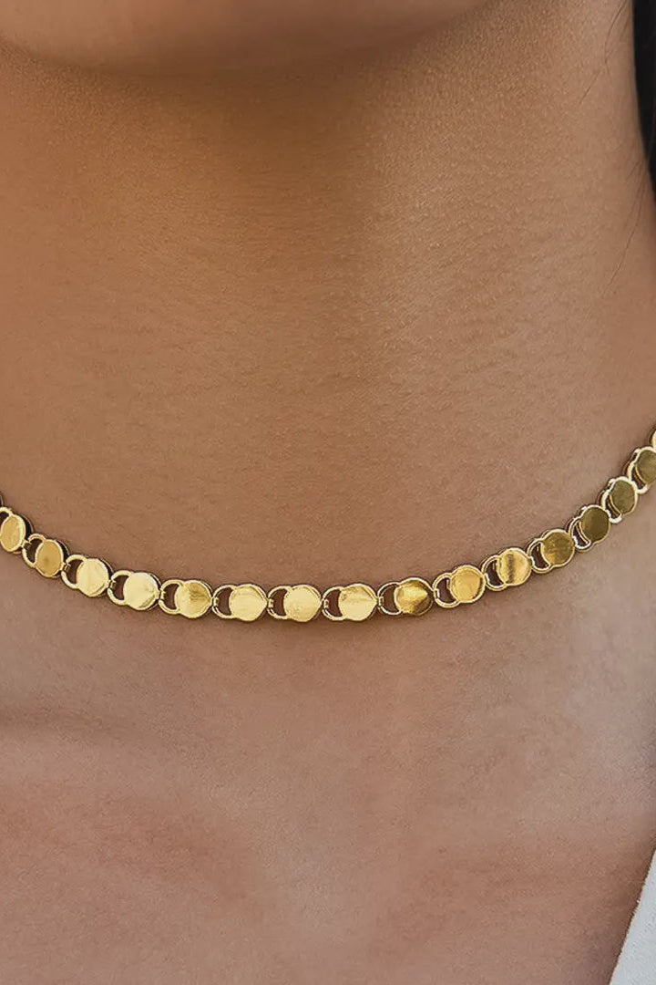 Gold necklace on a person's neck with a blurred background