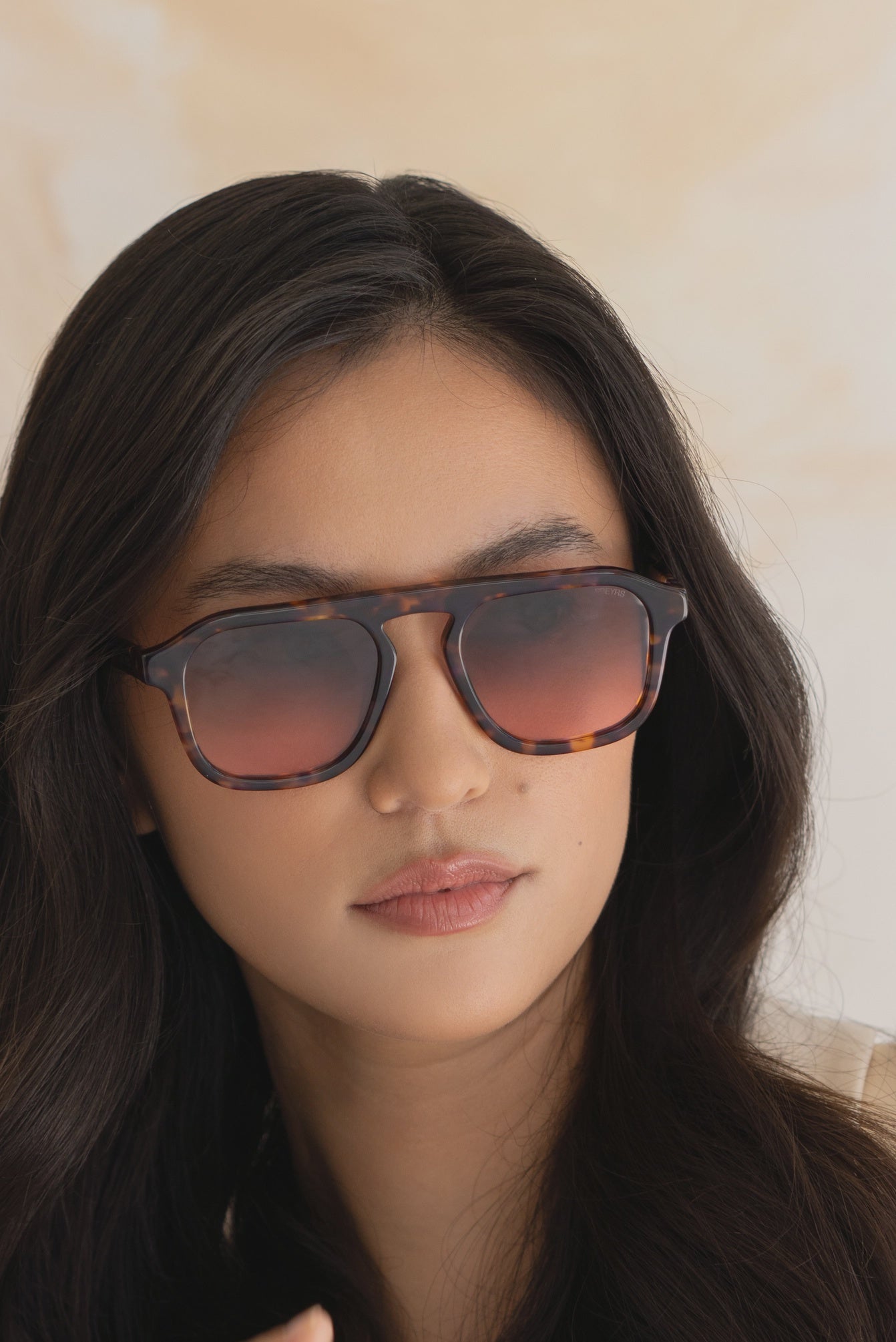 Woman wearing sunglasses with a neutral background