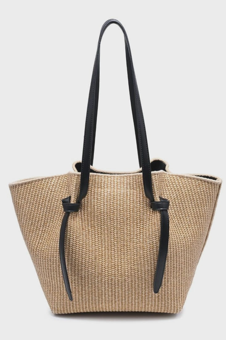 Beige straw tote bag with black handles on a white background