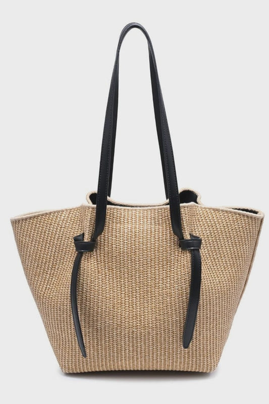 Beige straw tote bag with black handles on a white background