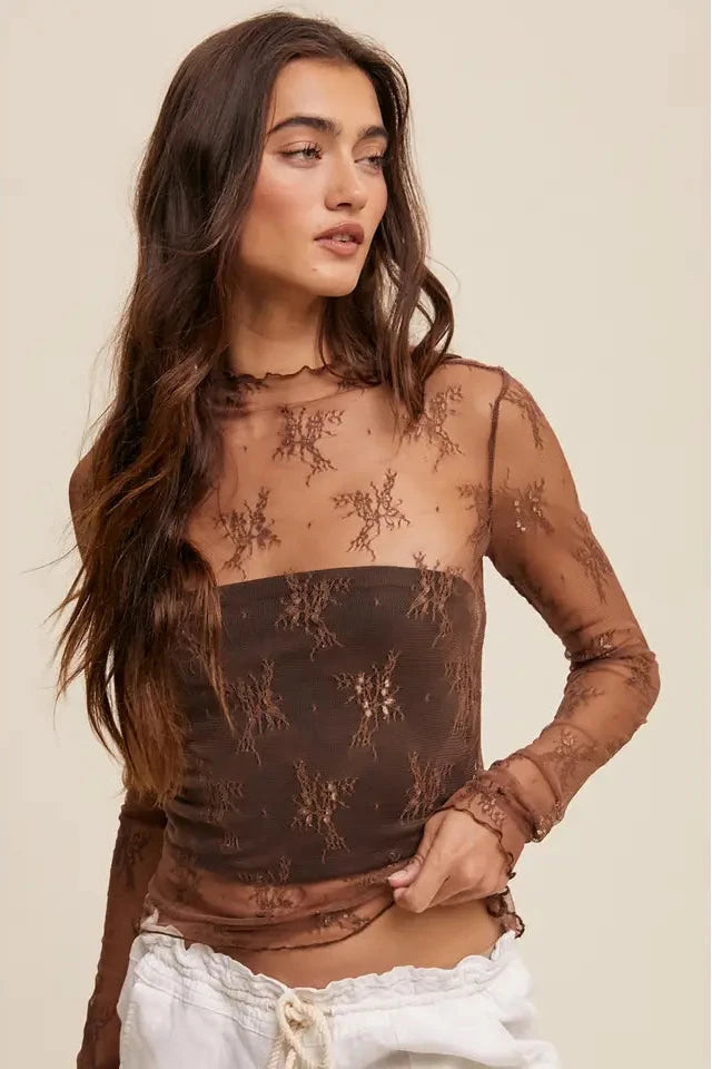Woman wearing a sheer brown top with lace details on a beige background