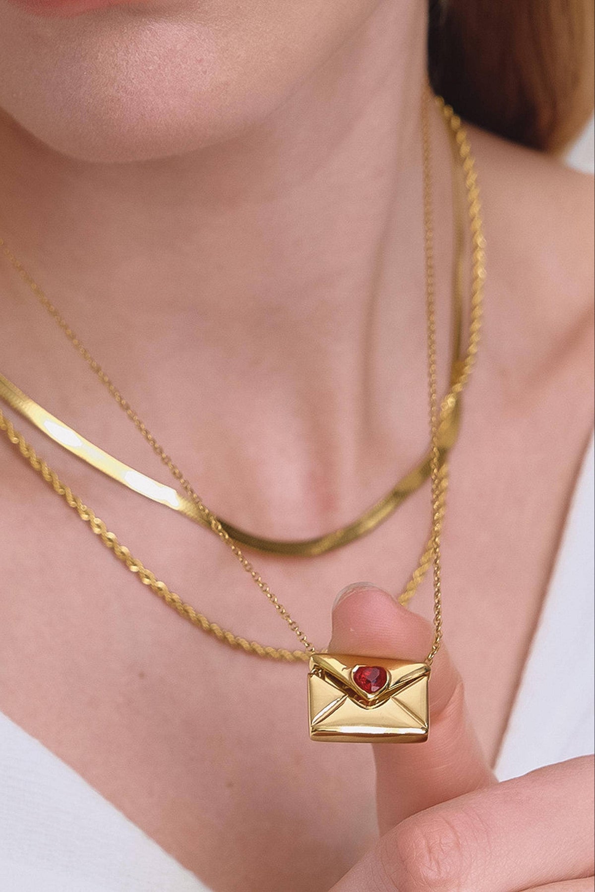 Gold necklace with a heart-shaped pendant worn by a person