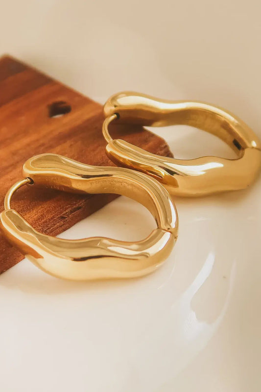 Gold hoop earrings on a wooden surface