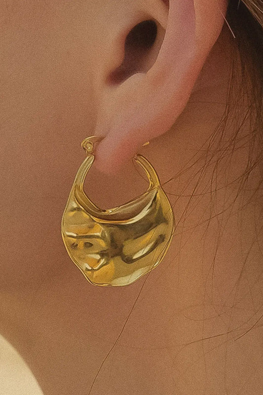 Gold hoop earring worn by a person with a blurred background