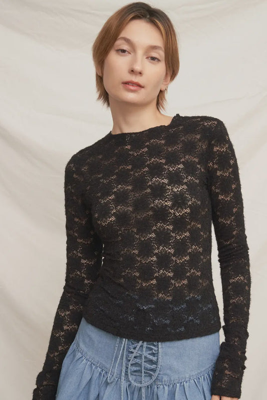 Woman wearing a black lace long-sleeve top against a plain background