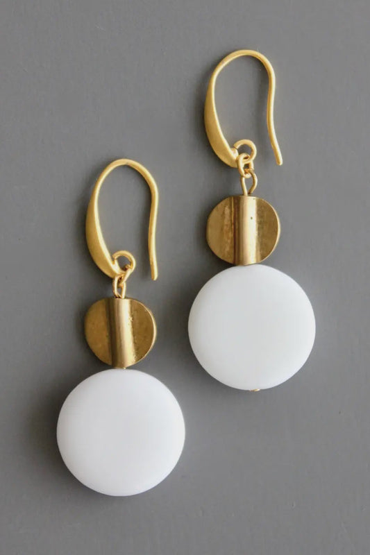 Gold and white earrings on a gray background