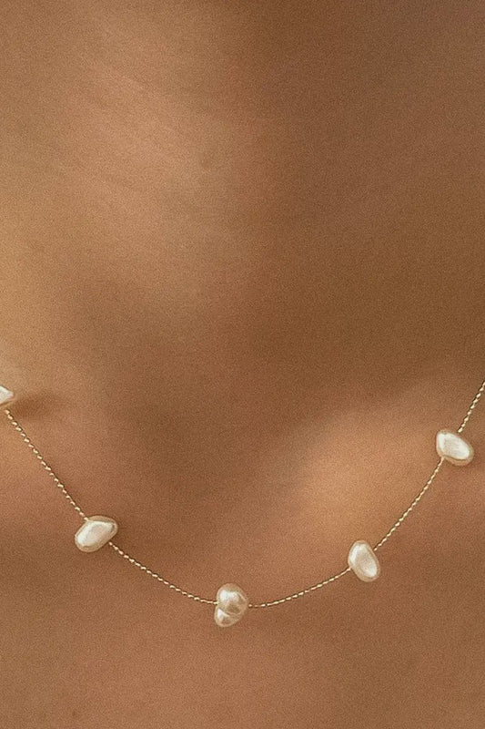 Pearl necklace on a person's neck with a neutral background