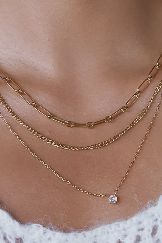 Gold chain necklaces on a person wearing a white lace garment