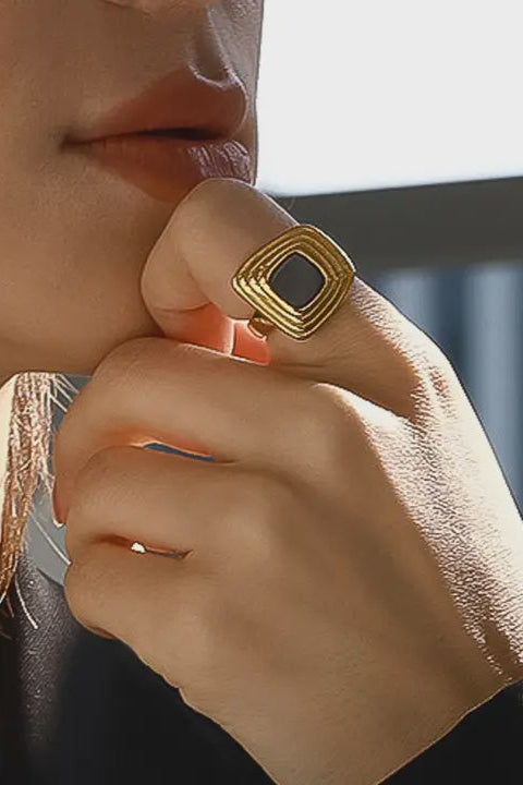 Close-up of a person wearing a gold ring with a black center.
