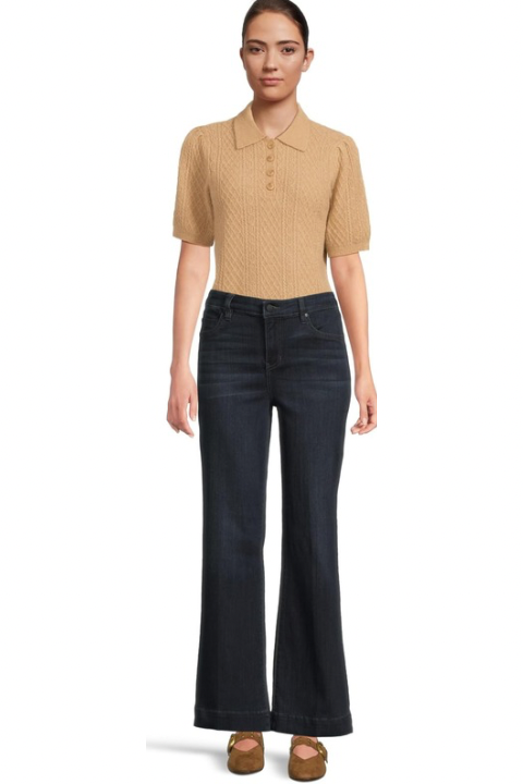 Woman wearing a beige short-sleeve shirt and dark blue jeans on a white background