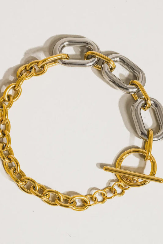 Two-tone gold and silver chain bracelet on a light gray background