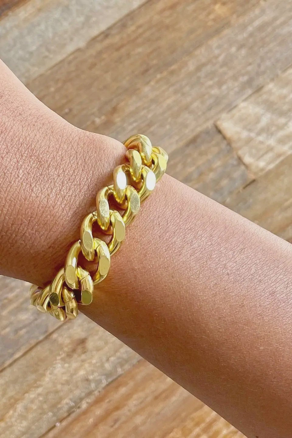 Gold chain bracelet on a wrist with a wooden background