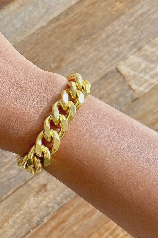 Gold chain bracelet on a wrist with a wooden background