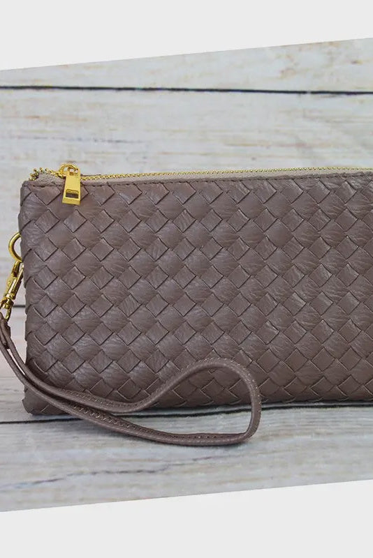 Brown woven clutch bag with gold zipper on a wooden surface