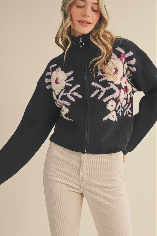 Woman wearing a black sweater with floral patterns on a beige background