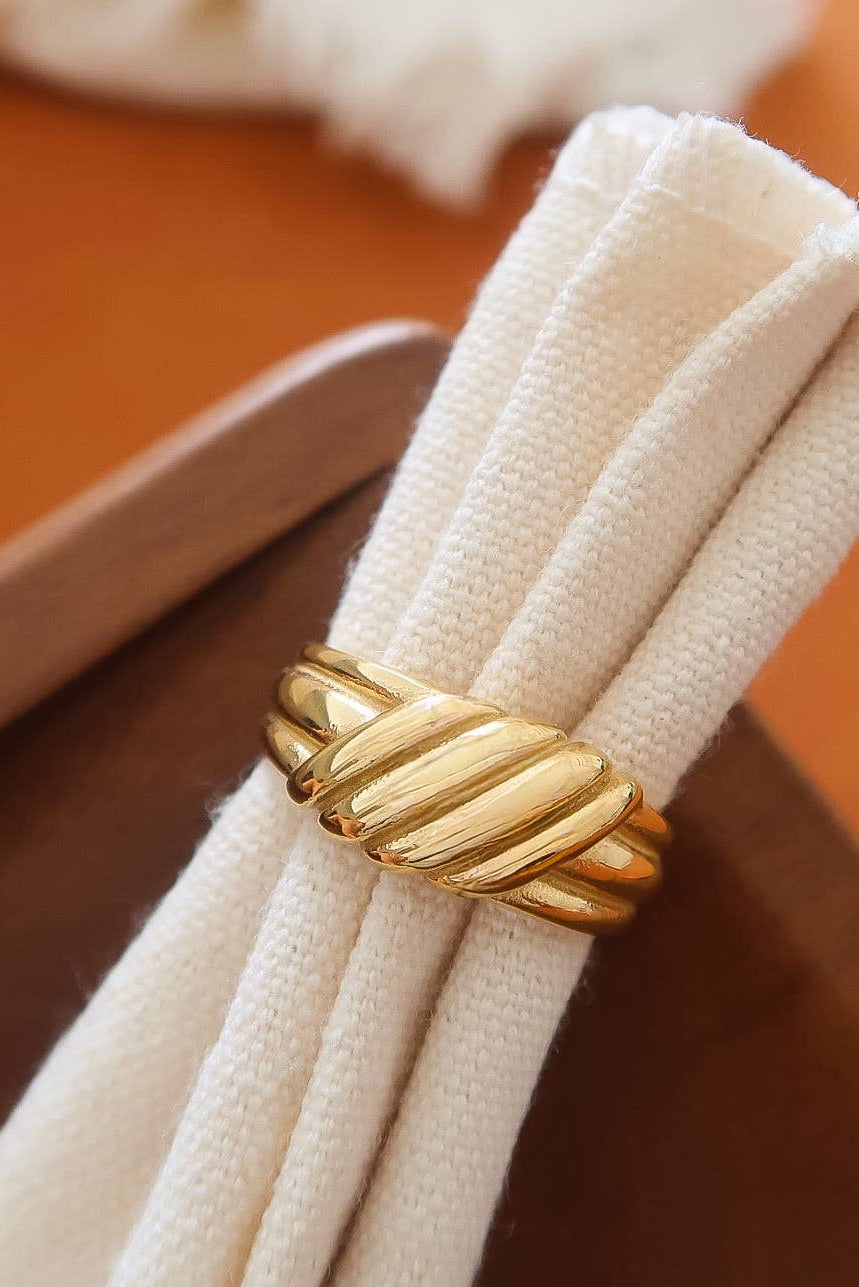 Gold ring on a white napkin with a wooden background