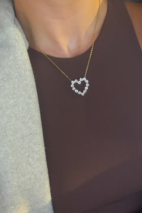 Heart-shaped necklace worn by a person with a neutral background