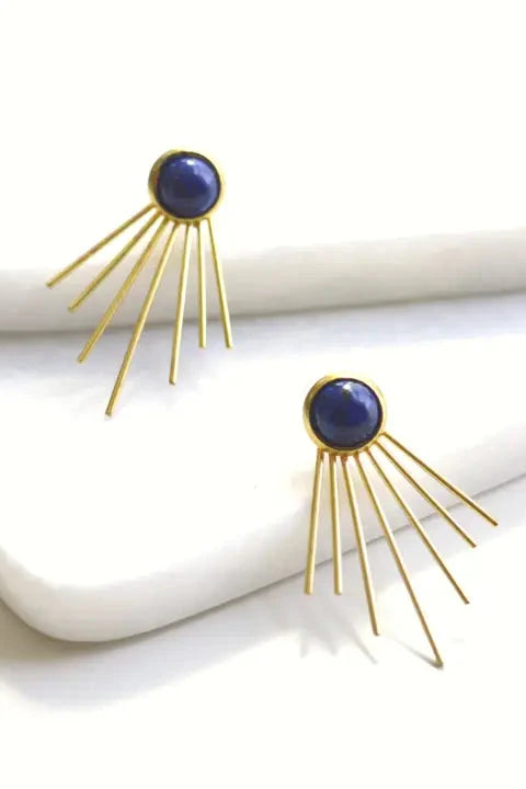 Gold earrings with blue gemstones on a white surface