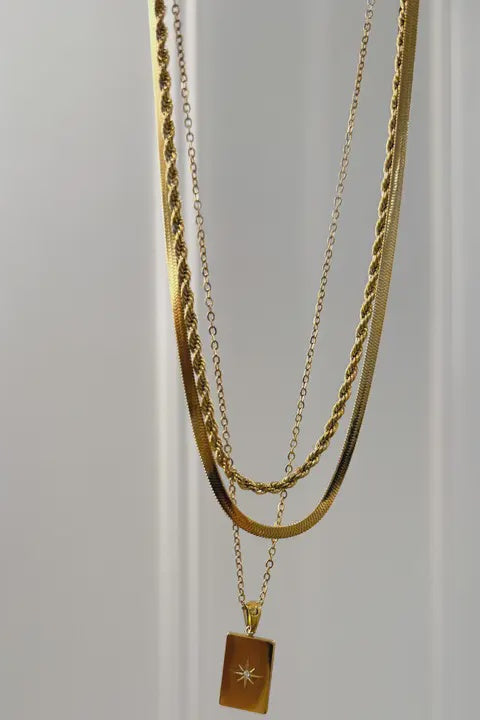 Two gold necklaces on a light gray background