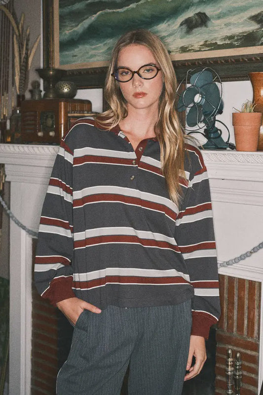 Woman wearing a striped sweater in a room with a fireplace and artwork.