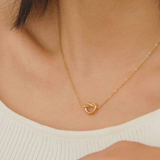 Gold necklace with a unique clasp on a person wearing a white top.