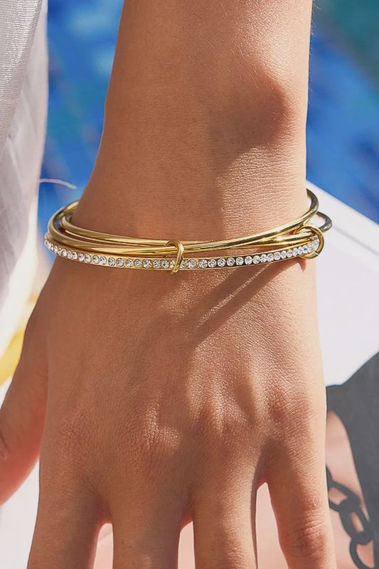 Gold bracelet with crystals on a wrist against a blurred beach background