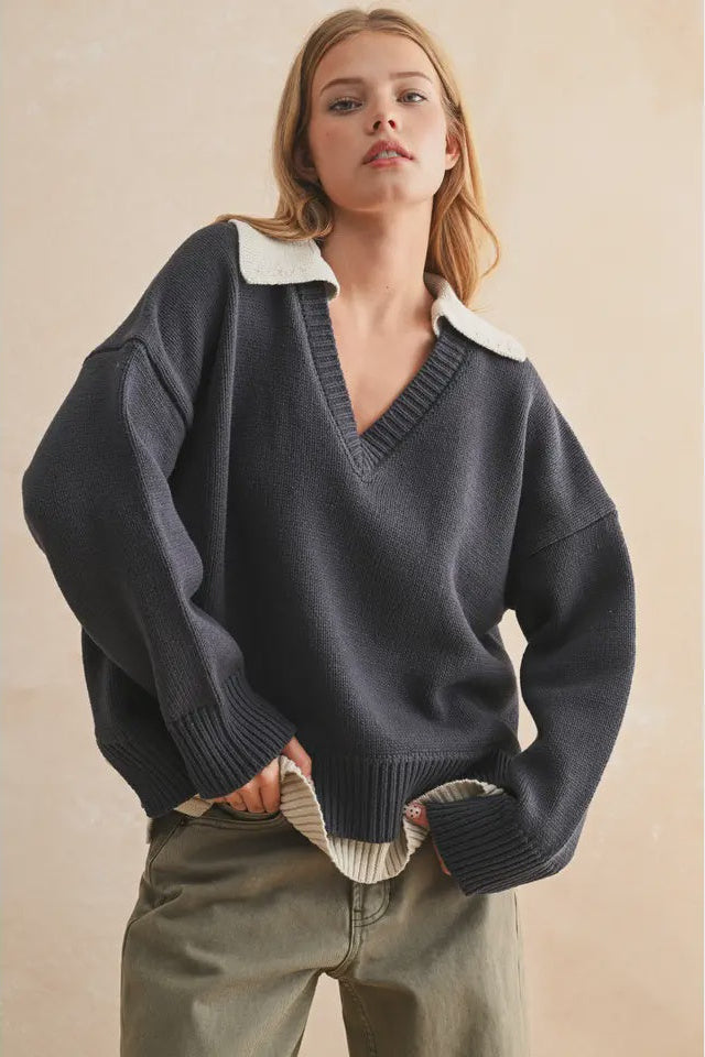 Woman wearing a dark blue sweater with white collar against a beige background