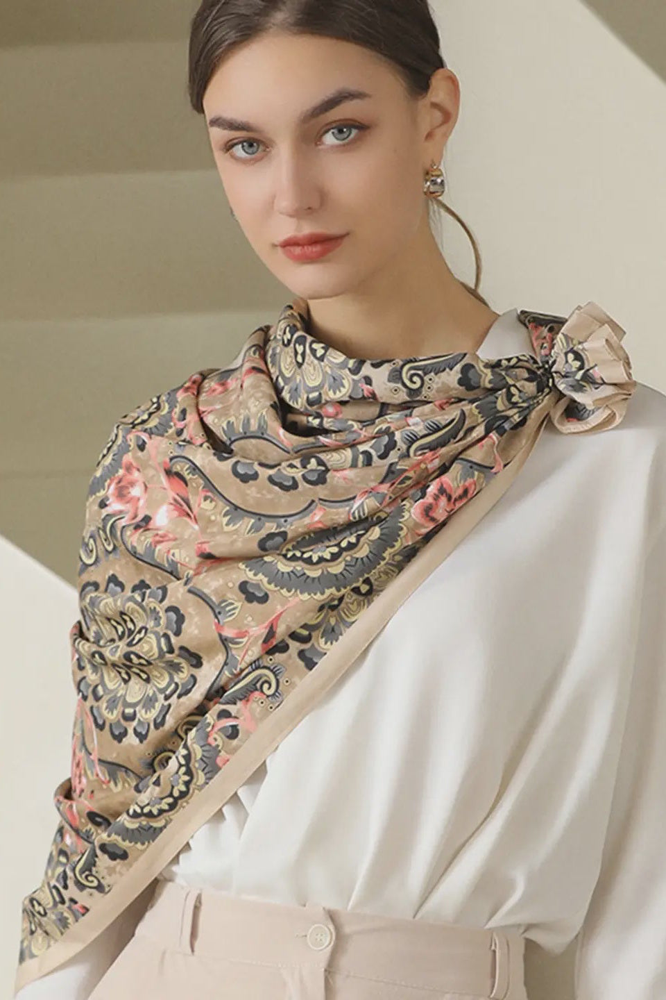 Woman wearing a patterned scarf with a neutral background