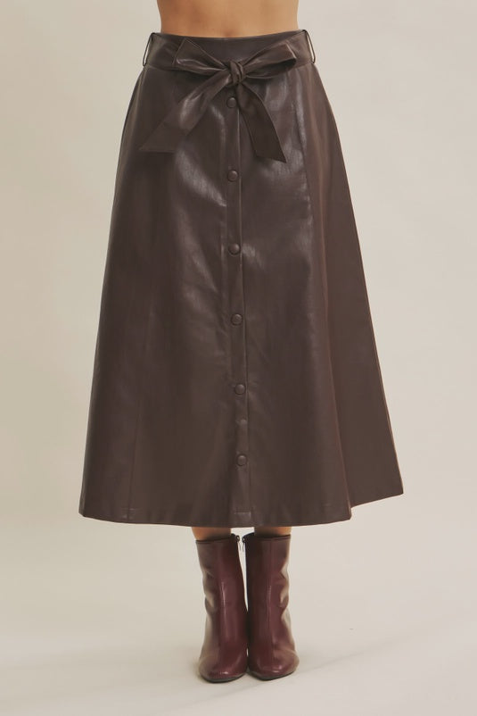 Brown leather skirt with buttons and a belt on a neutral background