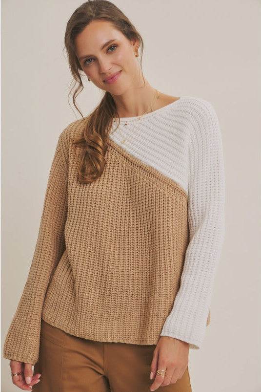 Woman wearing a two-tone sweater with beige and white colors on a plain background