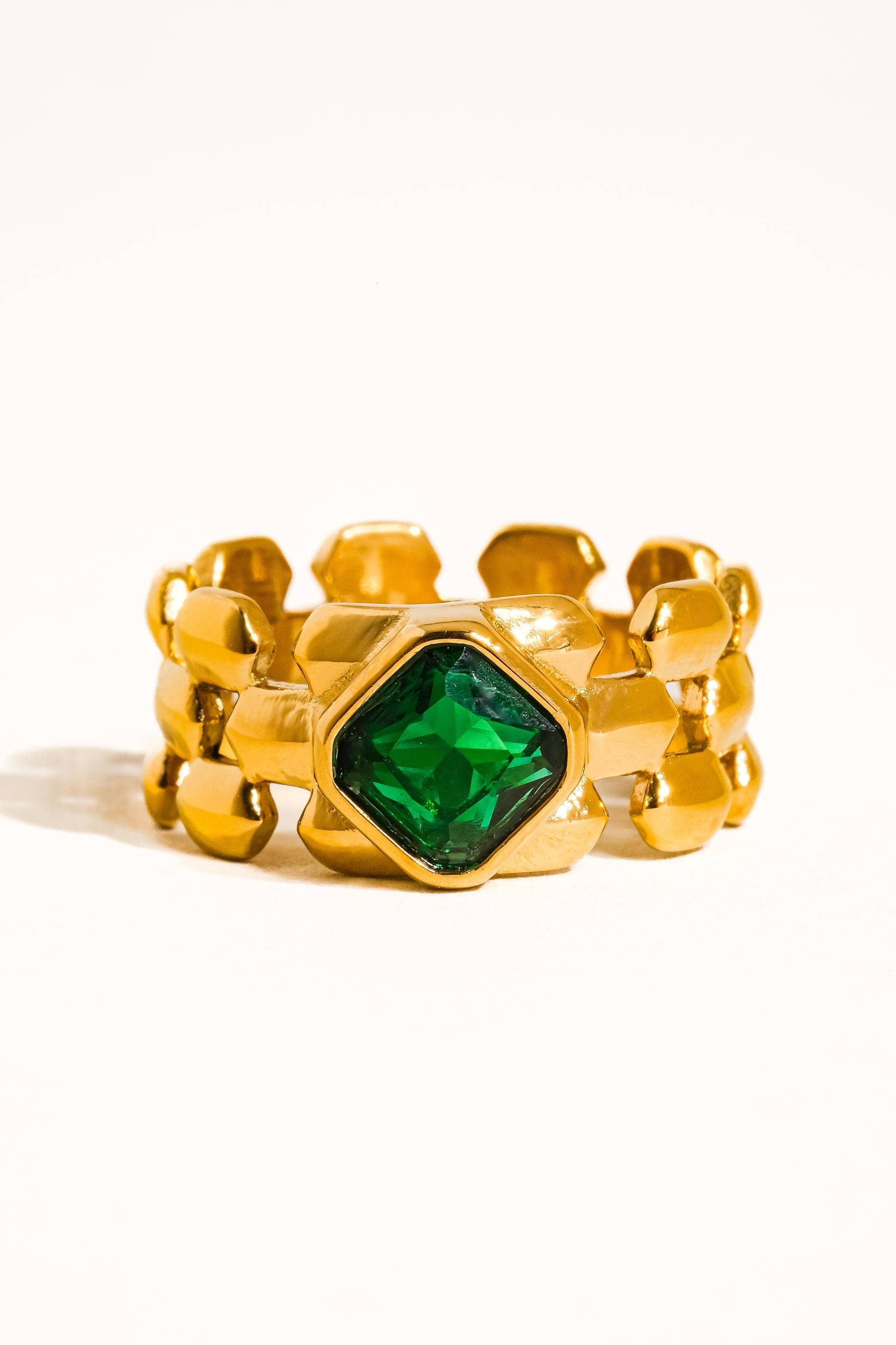 Gold ring with a green gemstone on a white background