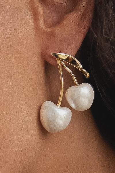 Gold and pearl earrings worn by a person