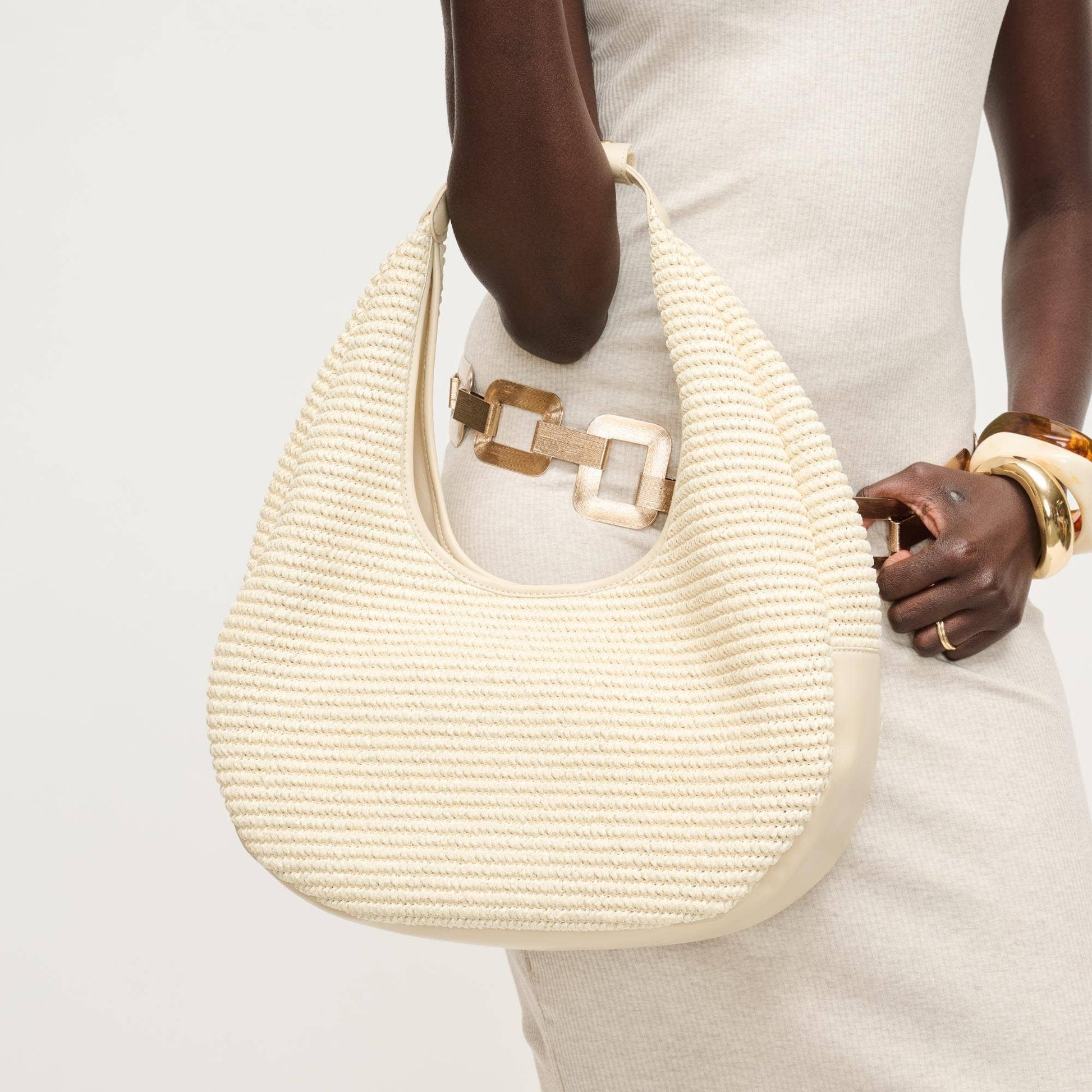 Beige woven handbag held by a person against a light background