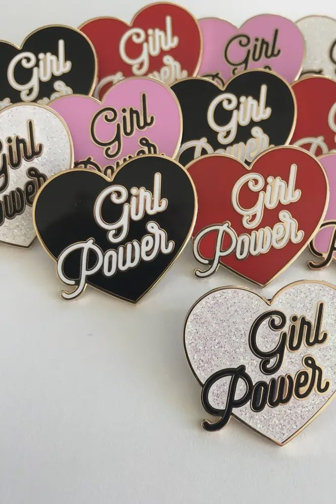 Heart-shaped pins with 'Girl Power' text in various colors on a white background