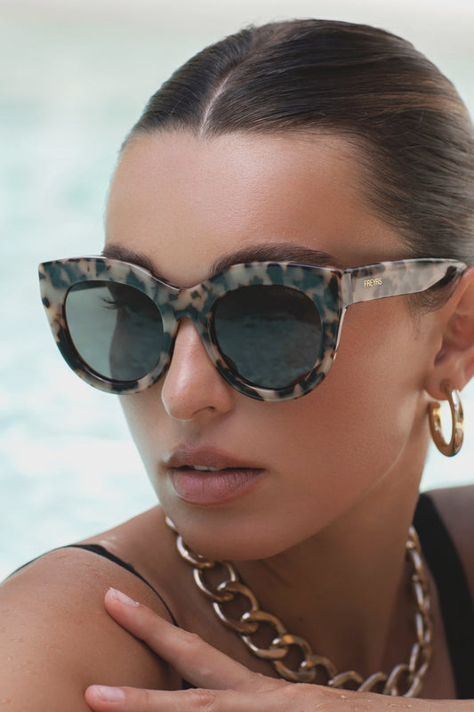 Woman wearing leopard print sunglasses with a blurred background